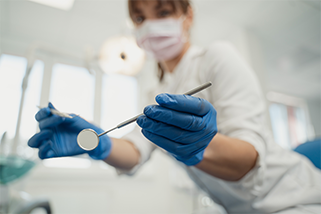 Zahnärztin mit Mundschutz und Behandlungsinstrumenten
